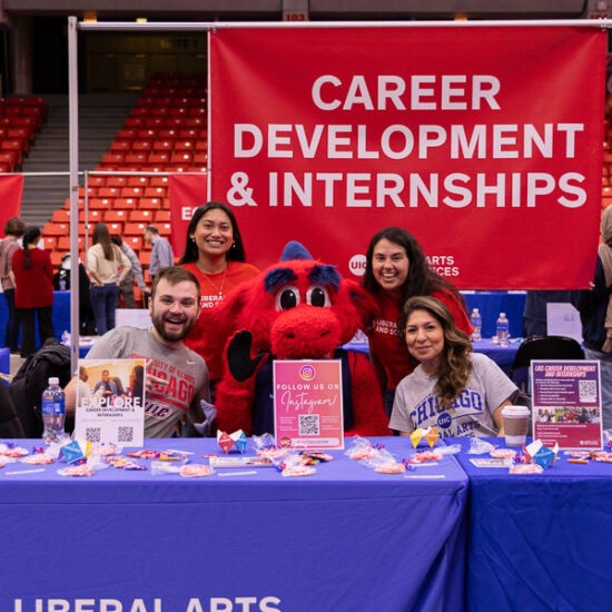 Career Development and Interships team sitting around UIC mascot at event