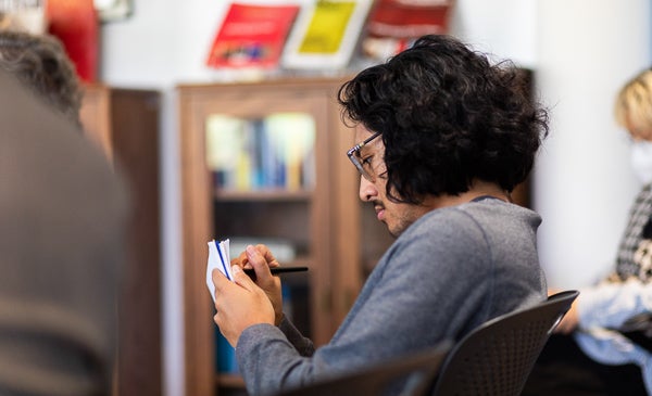 Student writing in notebook at Institute for the Humanities during reading event