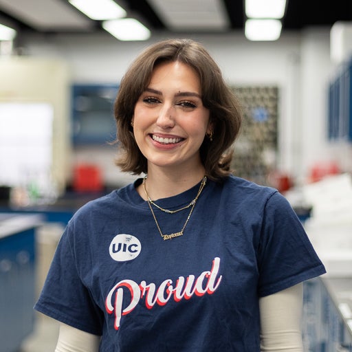 Earth and Environmental Sciences student smiling in blue UIC t shirt in a lab