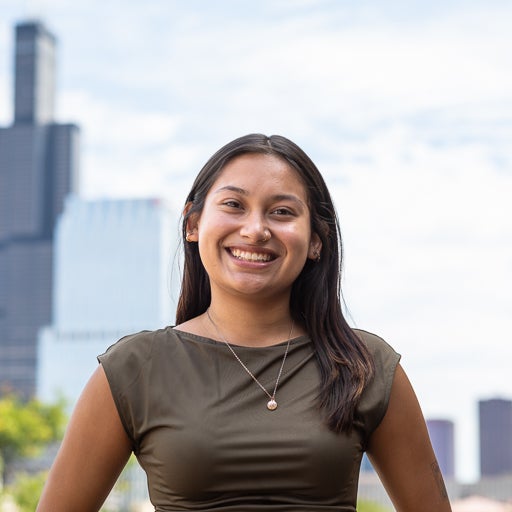 Student Jiselle Plata stands on UIC's campus with the Chicago skyline in the background