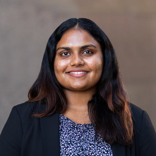 Political Science major wearing black blazer and blue floral shirt smiles on UIC's campus