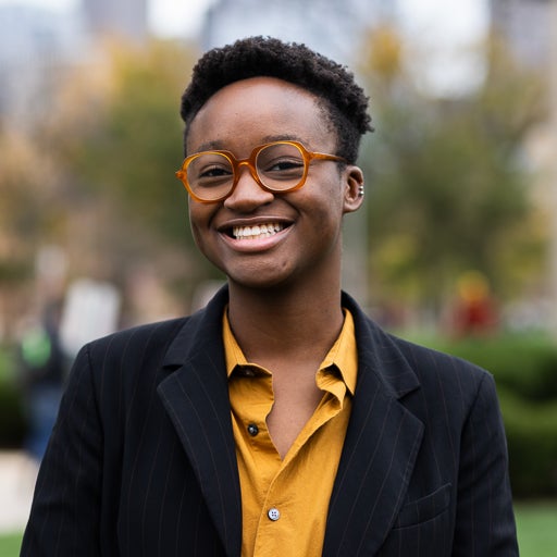 Black Studies student smiling in yellow button up and black blazer on campus