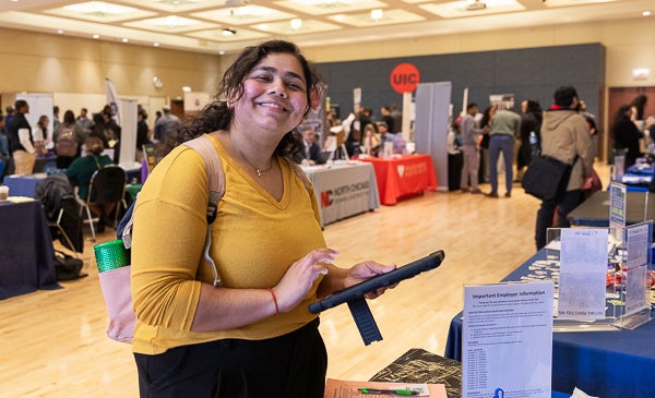 Student smiles and fills out forms on tablet during career fair