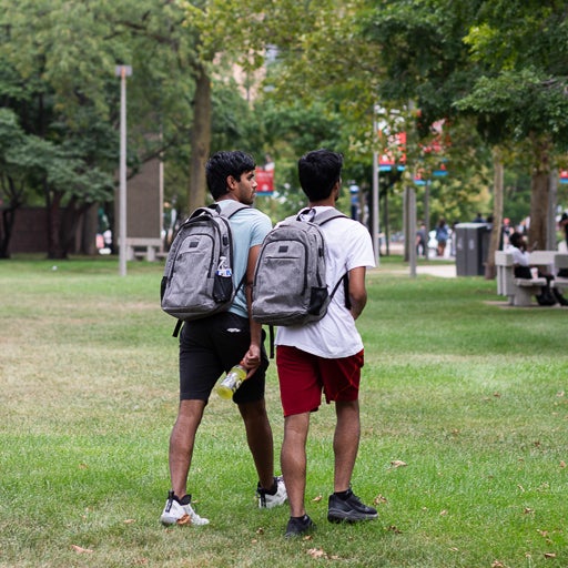 Students walking on grass with backpacks on